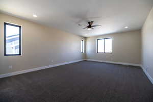 Empty room with dark carpet, baseboards, a ceiling fan, and recessed lighting