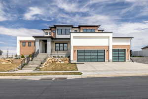 Contemporary house featuring concrete driveway, fence, and an attached garage