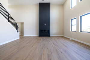Unfurnished living room featuring stairway, a high ceiling, a fireplace, and a healthy amount of sunlight