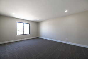 Unfurnished room featuring dark colored carpet, baseboards, and recessed lighting