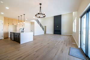 Kitchen with an inviting chandelier, open floor plan, light countertops, light wood-style floors, and a sink