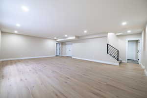 Basement featuring light wood finished floors, stairs, baseboards, and recessed lighting