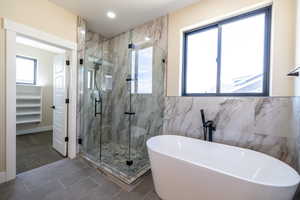 Bathroom featuring a freestanding tub, recessed lighting, tile patterned flooring, a marble finish shower, and tile walls