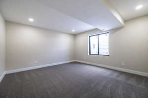 Empty room with recessed lighting, dark colored carpet, and baseboards