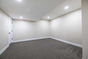 Finished below grade area with visible vents, dark colored carpet, baseboards, and recessed lighting