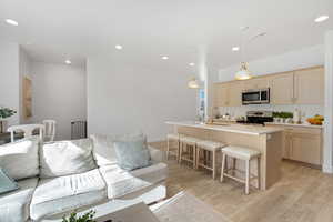 Living area with light wood-style flooring, visible vents, and recessed lighting