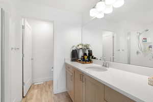 Bathroom with a shower stall, wood finished floors, vanity, and baseboards