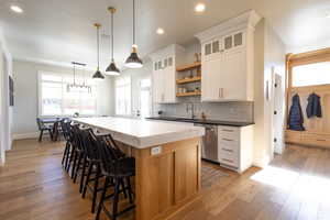 Kitchen with a center island, open shelves, a sink, light wood finished floors, and stainless steel dishwasher