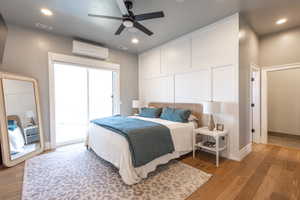 Main floor master suite, light wood-style floors, an mini split wall unit, baseboards