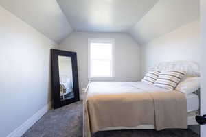 Bedroom with carpet flooring, baseboards, and lofted ceiling