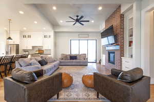 Living room featuring a brick fireplace, light wood-style floors, and ceiling fan