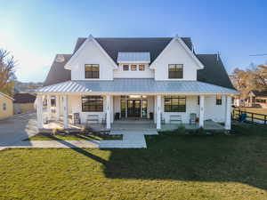 Rear view of property featuring a yard, covered porch, and a standing seam roof