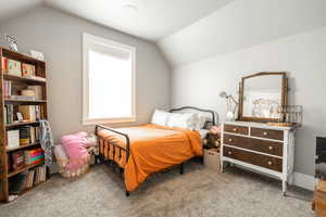 Bedroom with carpet floors and lofted ceiling