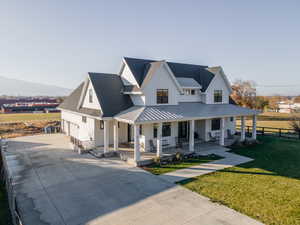 Modern farmhouse style home with concrete driveway, an attached garage, a front lawn, fence, and covered porch