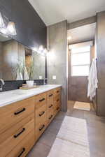 Master suite bathroom featuring tile patterned floors, double vanity, tile walls, soaker tub.
