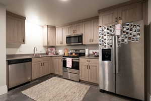 ADU Kitchen with dark countertops, concrete flooring, a sink, and appliances with stainless steel finishes