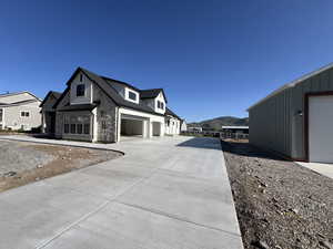 View of side of home featuring board and batten siding, driveway, a standing seam roof, and a residential view