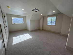Additional living space featuring light carpet, vaulted ceiling, recessed lighting, baseboards, and a textured ceiling