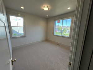 Spare room with baseboards, recessed lighting, and light colored carpet