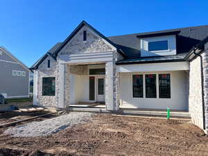View of front of property with a porch, metal roof, and stone siding