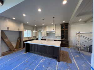Kitchen featuring a kitchen island, a sink, white cabinets, recessed lighting, and pendant lighting