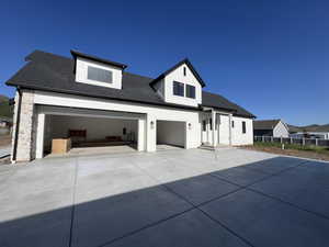 View of front of house with driveway, roof with shingles, and fence