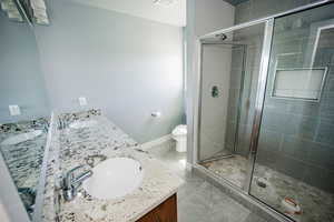 Full bath featuring a shower stall, double vanity, and a sink