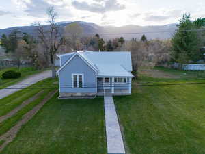 View of front facade with a front yard, a mountain view, and dirt driveway