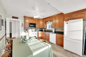 Kitchen with brown cabinetry, ceiling fan, a sink, and white appliances