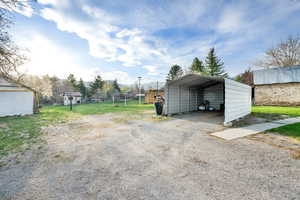View of vehicle parking with a detached carport and gravel driveway