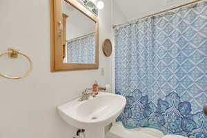 Full bath with curtained shower, a sink, and visible vents