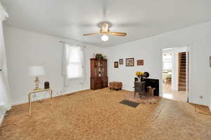 Interior space with ceiling fan, a wood stove, visible vents, carpet floors, and baseboards