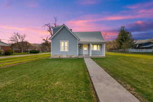 Bungalow-style home with a front lawn, fence, metal roof, and a porch