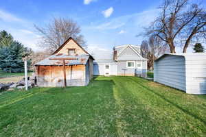 Back of house with a yard, metal roof, and an outbuilding
