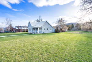 View of front of property featuring covered porch, a front yard, and metal roof