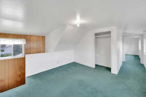 Additional living space with plenty of natural light, carpet, and lofted ceiling