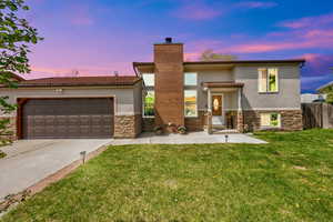 View of front of home featuring a yard, driveway, stucco & stone siding