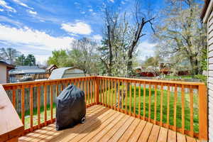 Wooden deck with a grill, a yard, fence, cherry tree, and a mountain view