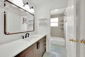 Updated full bathroom with toilet, tile floors, vanity, and shower / bath combination