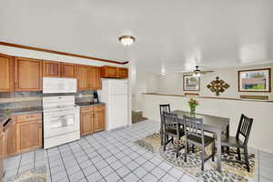 Kitchen featuring wood cabinets, light tile floors, large seating area, and white appliances