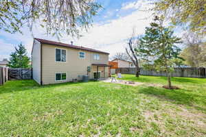 Back of house featuring a patio, a fenced backyard, a lawn, and central AC