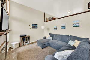Carpeted living area with a wealth of natural light, baseboards, high ceilings and a fireplace
