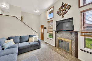 Carpeted living area with a wealth of natural light, baseboards, and a fireplace