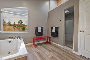 Bathroom with a tub to relax in, baseboards, and wood finished floors