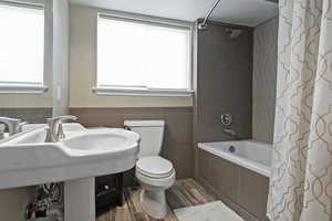 Full bath featuring tiled shower / bath combo, tile walls, and wood finished floors