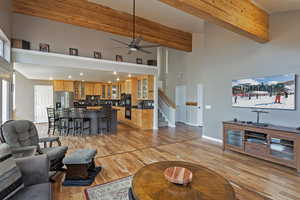 Living room with light wood-style floors, high vaulted ceiling, a ceiling fan.