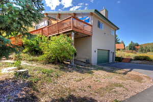 Rear view of house with driveway, a wooden deck, and a 2-car garage.