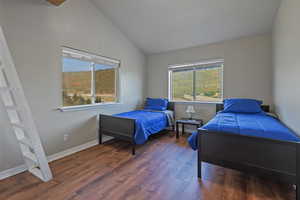 Bedroom featuring baseboards, vaulted ceiling, and wood finished floors
