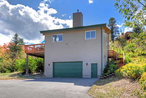 View of property with asphalt driveway, stairway, an attached 2-car garage, and a deck