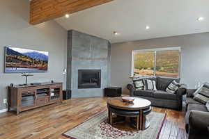 Living area with baseboards, a fireplace, recessed lighting, wood finished floors, and high vaulted ceiling